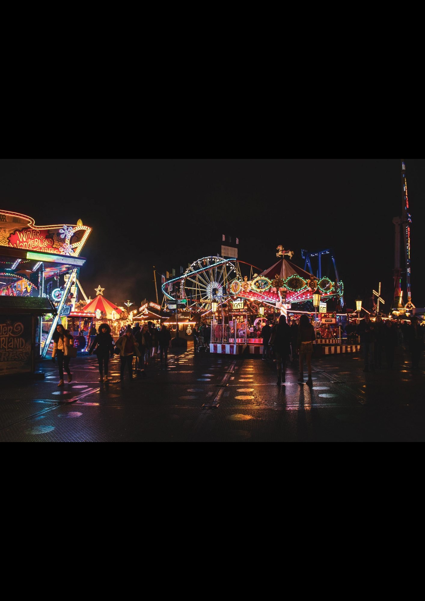 Festival grounds at night with rides and crowds